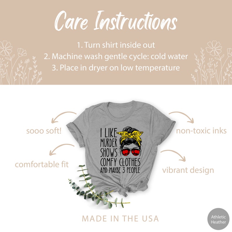 May include: Gray t-shirt with a black graphic of a woman with a messy bun and sunglasses. The text on the shirt reads "I like murder shows comfy clothes and maybe 3 people". The shirt is made in the USA.