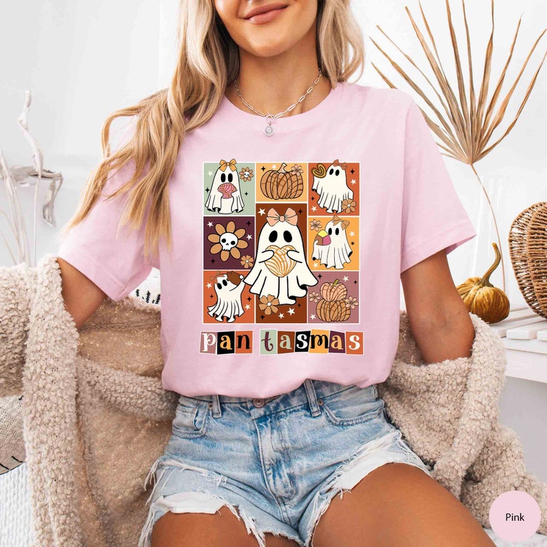 K&ouml;nnte beinhalten: Ein pinkfarbenes T-Shirt mit einem Aufdruck von Geistern, die Pan Dulce halten, ein traditionelles mexikanisches s&uuml;&szlig;es Brot, mit dem Text "Pan Tasm&aacute;s" in einer Retro-Schrift.