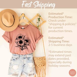 May include: A dusty rose t-shirt with a black sunflower graphic. The shirt is displayed with denim shorts, a straw hat, and a macrame bag. The words "Fast Shipping" are at the top.