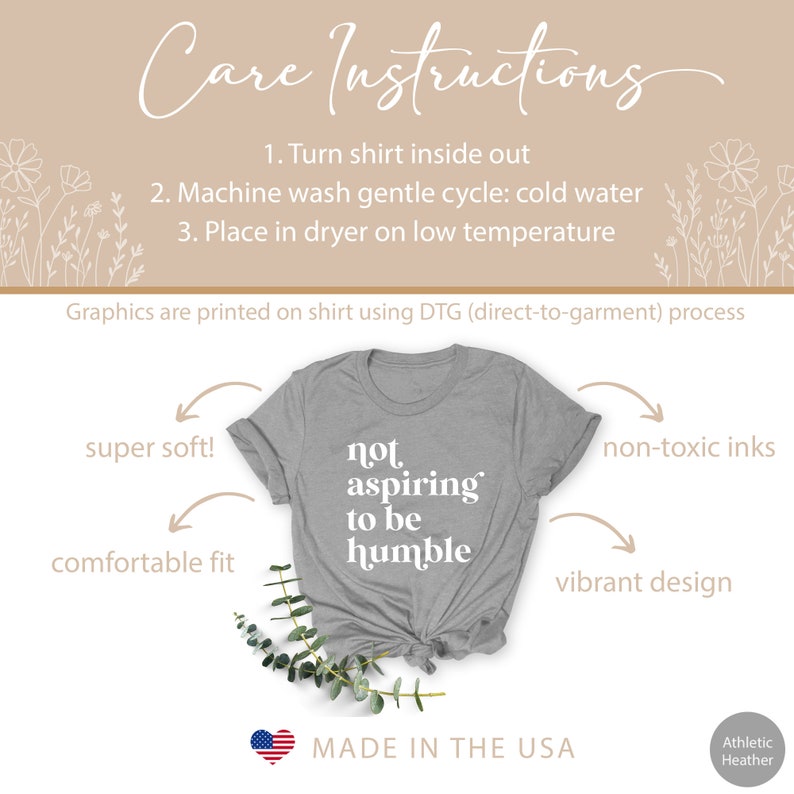May include: A gray t-shirt with the text "not aspiring to be humble" printed in white. The shirt is made in the USA and is super soft, comfortable, and features a vibrant design. The graphics are printed using a direct-to-garment process with non-toxic inks.