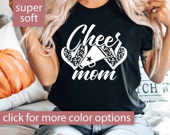 May include: Black t-shirt with white text that says "Cheer mom" and a graphic of a cheerleader's megaphone and pom-poms with a leopard print pattern.