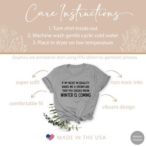 May include: Gray t-shirt with the text "If my belief in equality makes me a snowflake then you should know winter is coming". The shirt is made in the USA and is super soft, comfortable, and has a vibrant design.