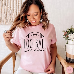 May include: A pink t-shirt with a black graphic of a football and the text "FOOTBALL mom".