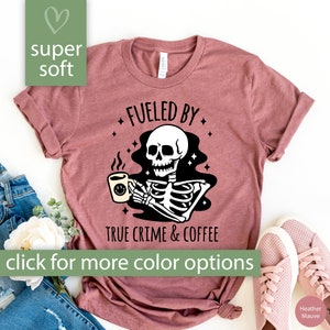 May include: A heather mauve t-shirt with a skeleton holding a coffee cup and the text "Fueled by True Crime & Coffee".