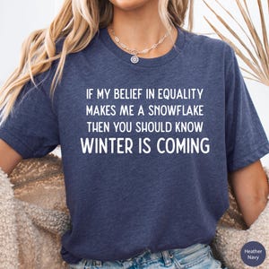 May include: A navy blue t-shirt with white text that reads "If my belief in equality makes me a snowflake then you should know winter is coming".