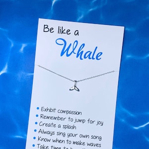 May include: A white card with the text "Be like a Whale" and a silver whale tail charm on a silver chain. The card lists six positive qualities: Exhibit compassion, Remember to jump for joy, Create a splash, Always sing your own song, Know when to make waves, Take time to breathe.