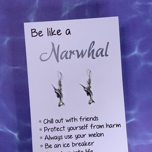 May include: A white card with the text "Be like a Narwhal" and a list of bullet points: "Chill out with friends", "Protect yourself from harm", "Always use your melon", "Be an ice breaker", "Dive deep into life", "Come up for air". Two silver narwhal earrings are displayed above the text.