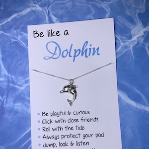 May include: A silver necklace with a dolphin charm and a card that reads "Be like a Dolphin" with a list of dolphin-like qualities: Be playful & curious, Click with close friends, Roll with the tide, Always protect your pod, Jump, look & listen, Remember to breathe.