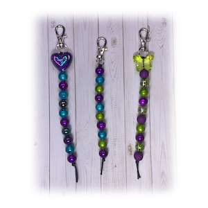 Joyas decorativas: Hermosa etiqueta para bolso, adorno para bolso o dije para agenda en tonos morado, azul y verde con cierre de mosquetón. Envío gratis.