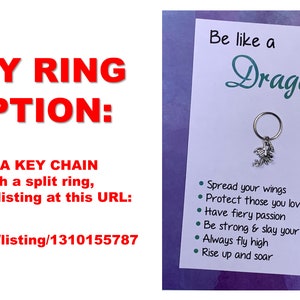 May include: A silver dragon keychain with a split ring. The keychain is attached to a card with the text "Be like a Dragon" and a list of dragon-themed affirmations: "Spread your wings", "Protect those you love", "Have fiery passion", "Be strong & slay your fears", "Always fly high", "Rise up and soar".