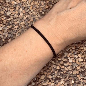 May include: A simple black bracelet made of thin cord.