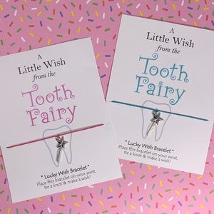 May include: Two cards with a tooth fairy theme. Each card has a silver tooth charm attached to a string bracelet. The text on the cards reads "A Little Wish from the Tooth Fairy" and "*Lucky Wish Bracelet* Place this bracelet on your wrist, tie a knot & make a wish!"