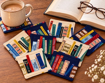 Puede incluir: Una colección de posavasos cuadrados de tela con ilustraciones impresas de lomos de libros con títulos como Gulliver's Travels, Treasure Island y Black Beauty. Los posavasos presentan varios colores, incluyendo azul marino, crema y rojo.
