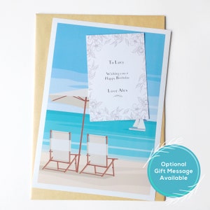 Puede incluir: Una tarjeta de cumplea&ntilde;os personalizada con una escena de playa con dos sillas, una sombrilla y un velero. La tarjeta incluye un mensaje que dice "To Lucy, Wishing you a Happy Birthday, Love Alex".