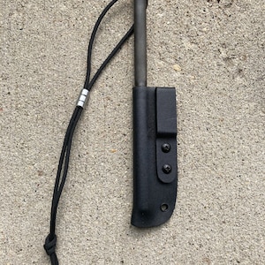 May include: A black leather sheath with a metal rod inside. The sheath has a black cord attached to it. The sheath has a metal snap closure.