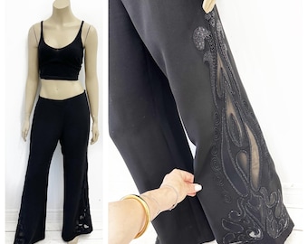 Pantalones negros glamurosos de pierna ancha con detalles transparentes en la pierna. Talla S/M.