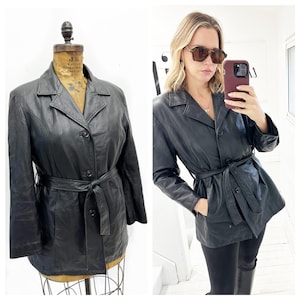 May include: A black leather jacket with a belt and button fastening. The jacket has a collar and long sleeves.