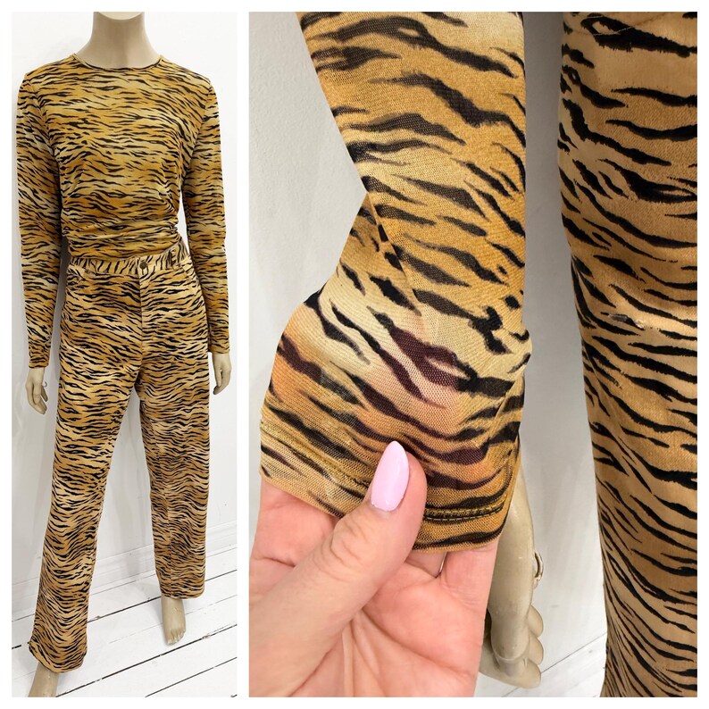 May include: A two-piece set featuring a long-sleeved top and pants. The outfit has a tiger stripe pattern in shades of brown and black. The fabric appears to be sheer and lightweight, with a close-up showing the sleeve detail.
