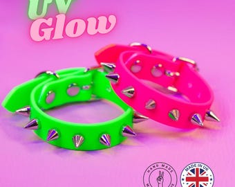 May include: Neon green and hot pink spiked bracelets. The bracelets have silver-colored spikes and buckles. The image includes the text "UV Glow" and two circular logos that say "Hand Made With Love" and "Made in UK".