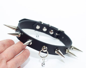 May include: Black leather choker with silver spikes and dangling bells. The choker is adjustable and has a buckle closure.