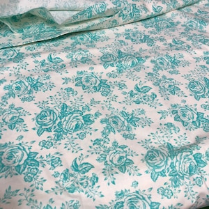 Peut inclure: Tissu blanc avec un motif floral turquoise de roses et de feuilles.