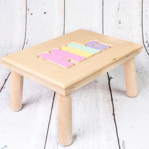 May include: A wooden step stool with four legs and the word "MIA" spelled out in colorful letters on the top.