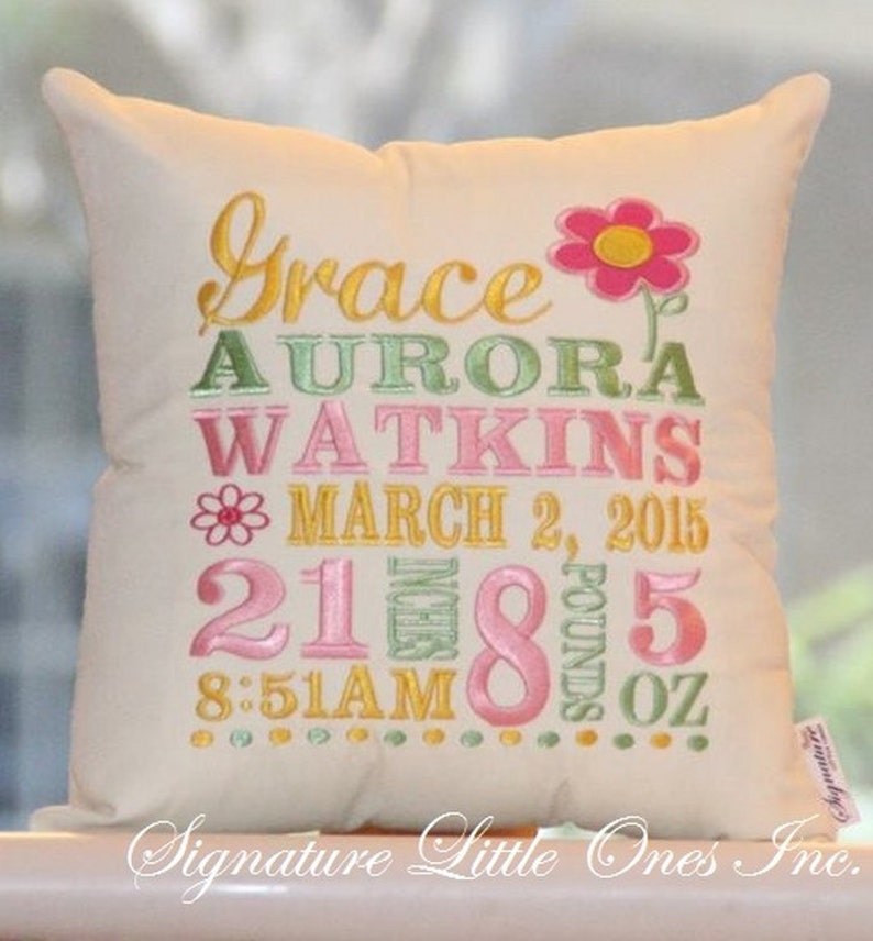 May include: A white pillow with embroidered text in pink, green, and yellow. The text reads "Grace Aurora Watkins March 2, 2015 21 inches 8 pounds 5 oz 8:51 AM".