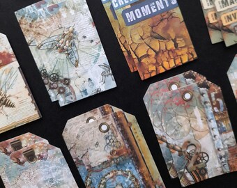 May include: A collection of vintage-style paper tags with various designs, including a steampunk-inspired insect, a cracked earth background, and the text "Create Moments". The tags are printed on textured paper and have a distressed look.