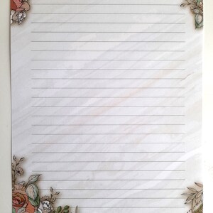 May include: A lined sheet of paper with a floral border. The border features pink and white roses, green leaves, and a light green and white background.