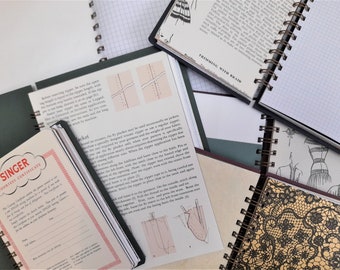 Puede incluir: Una colección de cuadernos de espiral con diferentes cubiertas, incluyendo una cubierta verde con instrucciones de costura, una cubierta negra con un patrón de cuadrícula, una cubierta marrón con un patrón de encaje y una cubierta blanca con el logotipo de una máquina de coser Singer y un borde rojo y blanco. El texto en la cubierta verde dice "Singer Courtesy Certificate".