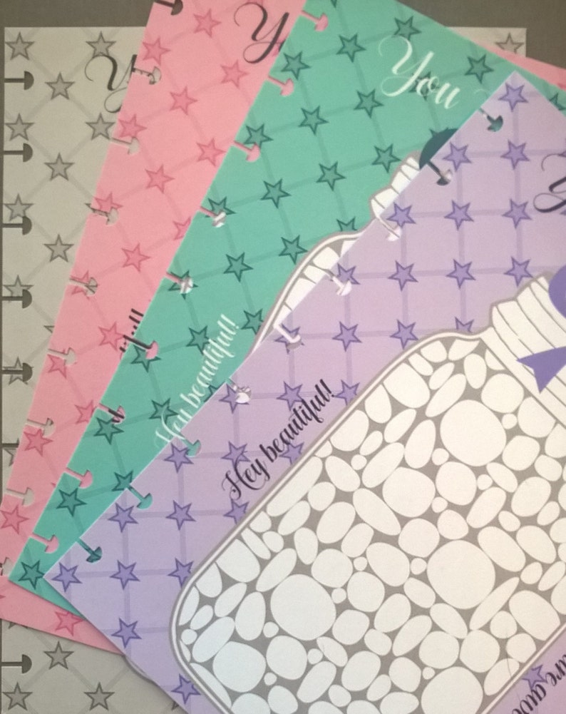 May include: Four colorful patterned paper sheets with a star design. The top sheet is light green with white stars, the second sheet is pink with white stars, the third sheet is light purple with white stars, and the bottom sheet is gray with white stars. The text "You" is written on the top sheet and the text "Hey beautiful!" is written on the third sheet.
