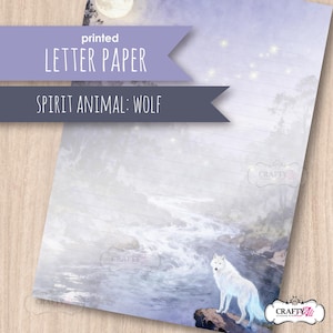 May include: A sheet of lined letter paper featuring a printed illustration of a white wolf standing on a rock by a flowing river in a misty forest under a full moon. The paper includes the text printed letter paper and spirit animal: wolf.