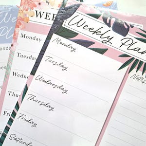 Könnte beinhalten: Wochenplaner mit floralen und tropischen Blattmustern. Jeder Planer hat einen rosa Rand und Platz für Notizen. Die Wochentage sind in einer handschriftlichen Schriftart aufgeführt. Der Text "Weekly Planner" steht oben.