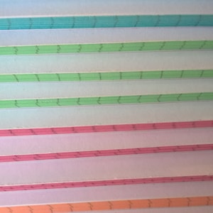 May include: A stack of colorful paper with a wavy line pattern. The paper is in shades of blue, green, pink, and orange.
