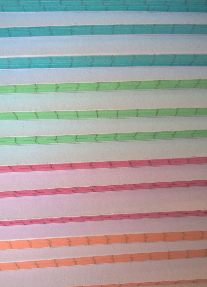 May include: A stack of colorful paper with a wavy line pattern. The paper is in shades of blue, green, pink, and orange.
