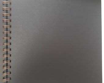 May include: A black spiral bound notebook with a copper coil binding.