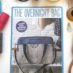 May include: A sewing pattern for a blue and white overnight bag with a stag print. The pattern includes instructions for making the bag and learning basic bag-making skills. The text on the pattern reads "The Overnight Bag" and "Learn Bag-Making Skills".