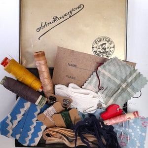 May include: A vintage Players Navy Cut tin filled with sewing supplies, including spools of thread, buttons, fabric scraps, and a needle threader. The tin has a label that says "John Player & Sons" and a Players Navy Cut stamp.