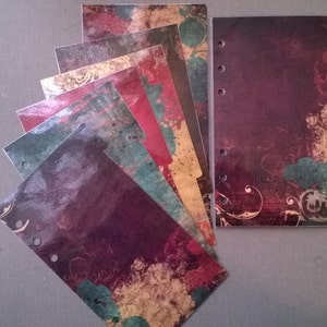 May include: A set of eight colorful, patterned dividers for a planner or notebook. The dividers have a distressed, vintage look with shades of red, green, and gold. Each divider has a hole punched at the top for easy insertion into a binder.