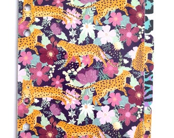 May include: A purple planner cover with a repeating pattern of orange leopards and pink, white, and red flowers. The planner has a set of colorful dividers with animal print designs.