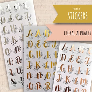 May include: Sheets of foiled alphabet stickers with floral designs in gold, silver, and rose gold. The image includes the text "foiled STICKERS" and "FLORAL ALPHABET".