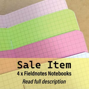 May include: Four colorful Fieldnotes notebooks in shades of pink, green, yellow, and lavender. Each notebook has a grid pattern on the pages. The text "Sale Item" and "4 x Fieldnotes Notebooks" is displayed on the bottom of the image.