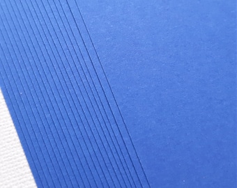 May include: A stack of blue cardstock paper with a textured surface.