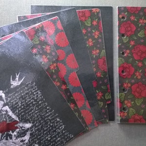 May include: A collection of planner inserts and dividers with a dark, romantic aesthetic. The inserts feature a mix of floral and botanical patterns in red, black, and white. The planner cover has a rose pattern.