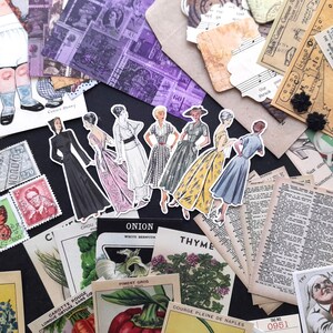 May include: A collection of vintage ephemera, including paper dolls, stamps, and botanical illustrations. The paper dolls are dressed in 1950s style clothing. The stamps are from various countries and feature different designs. The botanical illustrations are of onions, thyme, and other plants. The ephemera is arranged on a black surface.