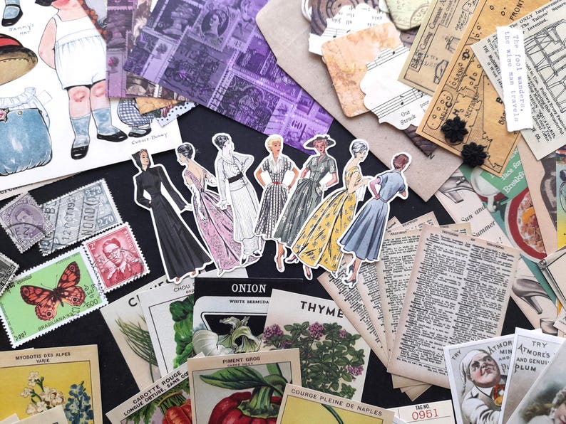 May include: A collection of vintage ephemera, including paper dolls, stamps, and botanical illustrations. The paper dolls are dressed in 1950s style clothing. The stamps are from various countries and feature different designs. The botanical illustrations are of onions, thyme, and other plants. The ephemera is arranged on a black surface.