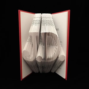 May include: A book with red covers is folded into a three-dimensional shape that resembles the letters "JB".