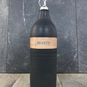 K&ouml;nnte beinhalten: Schwarze Keramik-&Ouml;l- und Essigflasche mit einem Holzetikett mit der Aufschrift "PEANUT".
