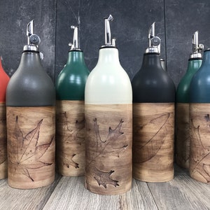 May include: Set of six ceramic oil and vinegar bottles with a wood-look finish and a leaf design. The bottles are in various colors, including orange, gray, green, white, black, and blue.