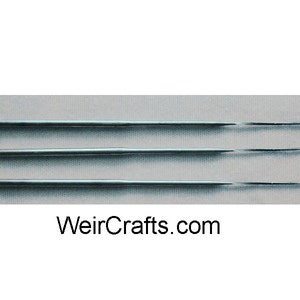 May include: Four silver knitting needles with a bent tip. The needles are arranged in a row on a gray surface. WeirCrafts.com is printed below the needles.
